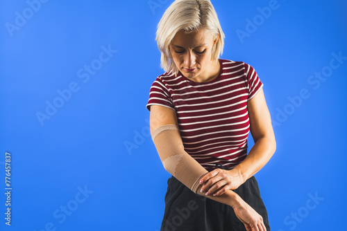woman wearing an elbow support brace on a blue background, copy space trauma and healing concept. High quality photo