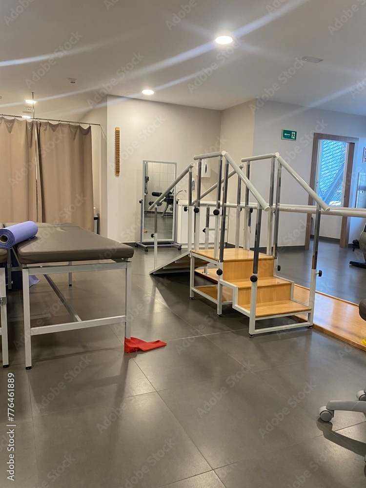 A well-equipped physical therapy room with various rehabilitation equipment, including parallel bars and therapy mats.
