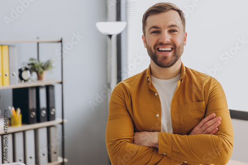 Portrait of a modern businessman man in a yellow shirt smiling with healthy teeth in the office