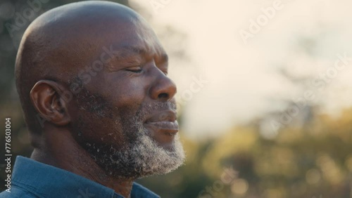 Close up of smiling senior man outdoors in countryside relaxing closing eyes and taking deep breaths of fresh air - shot in slow motion