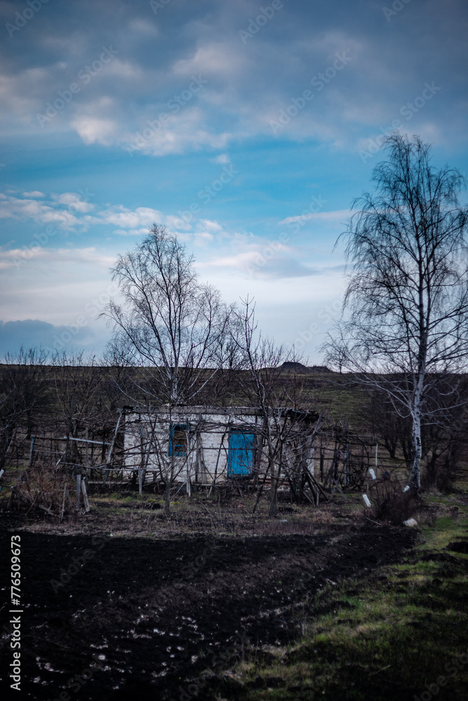 Old abounded houses in the old village . Spring mystery countryside . House in forest , blue clouds . Sunset over the hose . Damaged houses 