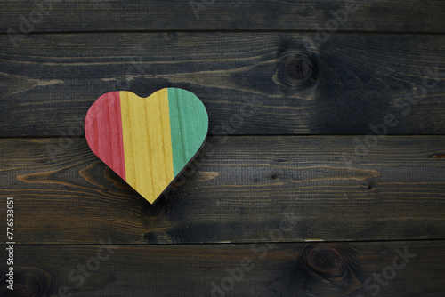 wooden heart with national flag of guinea on the wooden background. photo
