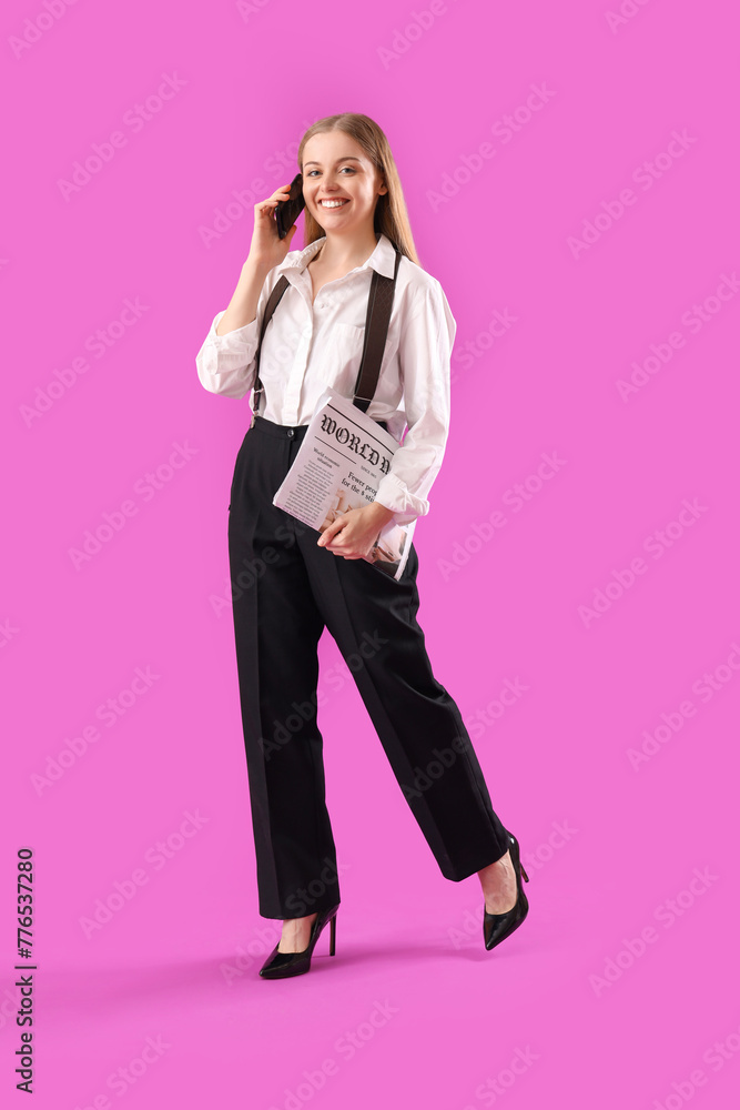 Stylish young businesswoman with newspaper talking by mobile phone on purple background Stylish young businesswoman with newspaper talking by mobile phone on purple background