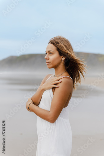 Vertical portrait of latina girl on the beach posing. Concept of peace, solitude, tranquility and self-care. © Alberto