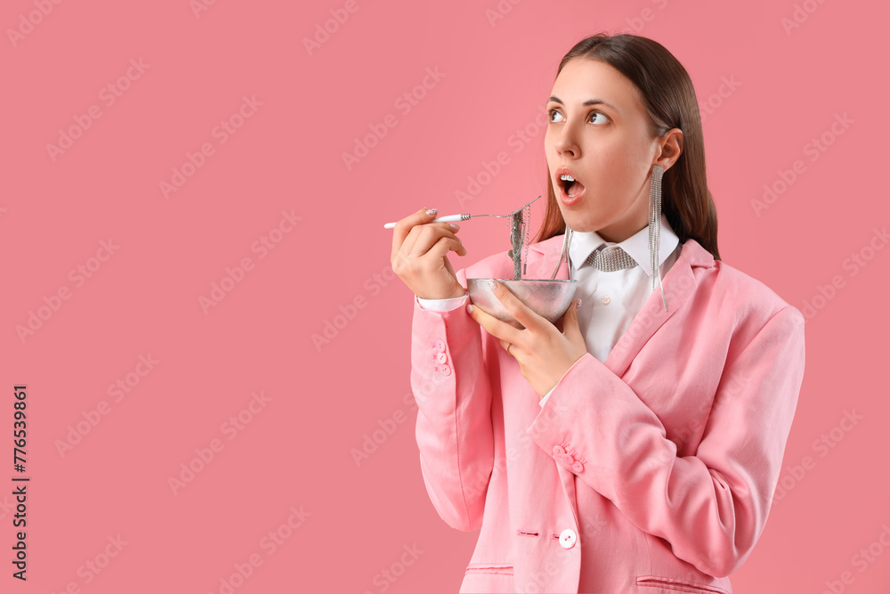 Woman with bowl eating jewelry on pink background Woman with bowl eating jewelry on pink background
