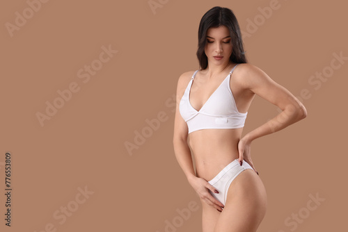 Pretty young woman in beautiful white underwear on brown background © Pixel-Shot