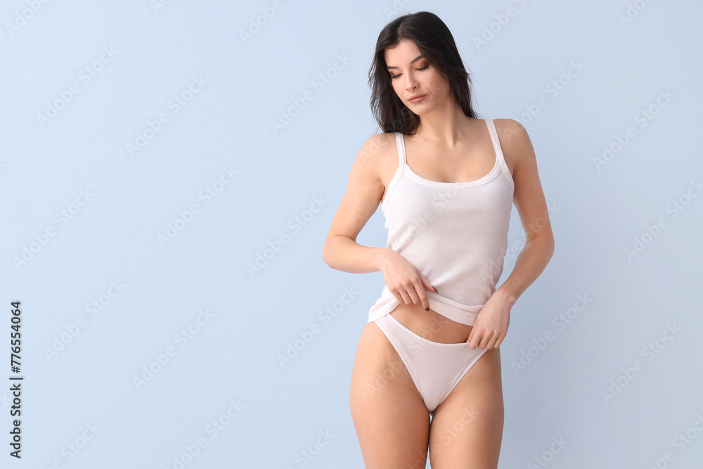 Beautiful young woman in white underwear on blue background Beautiful young woman in white underwear on blue background