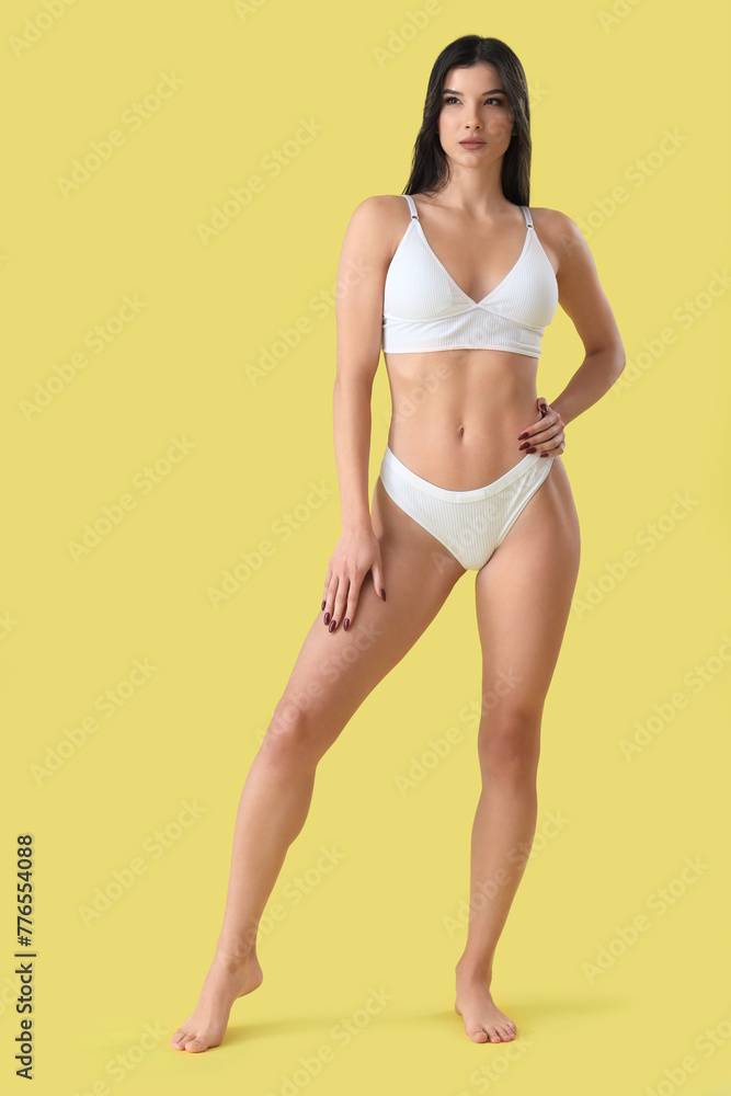 Obraz premium Beautiful young woman in white underwear on yellow background