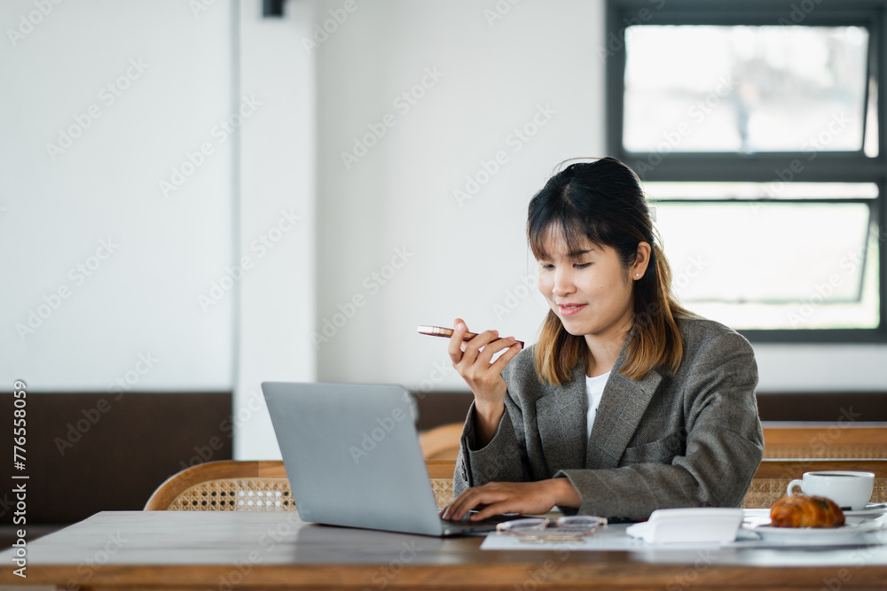Multitasking businesswoman is on a phone call, with her laptop open in a relaxed cafe workspace. Multitasking businesswoman is on a phone call, with her laptop open in a relaxed cafe workspace.