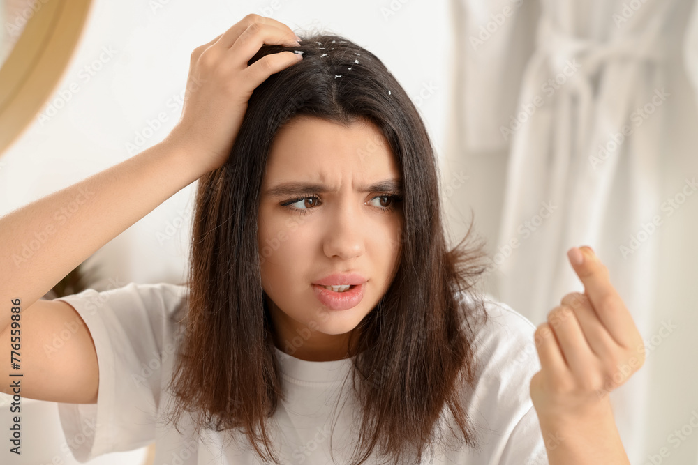 Stressed young woman with dandruff problem in light bathroom Stressed young woman with dandruff problem in light bathroom