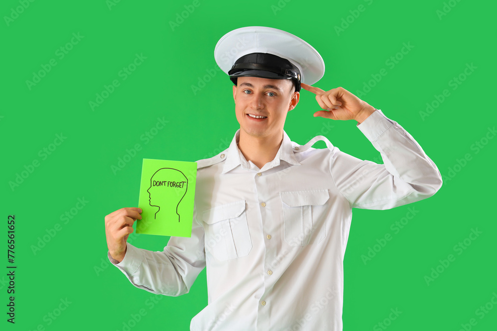 Male pilot holding paper with text DON'T FORGET and pointing at his head on green background Male pilot holding paper with text DON'T FORGET and pointing at his head on green background