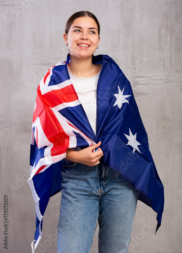 Joyful girl stands with flag of Australia .Isolated on gray background