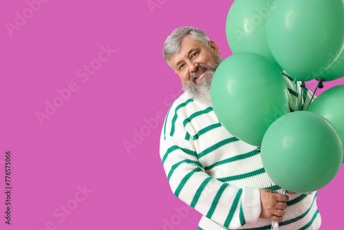 Senior man with bunch of green balloons on pink background © Pixel-Shot