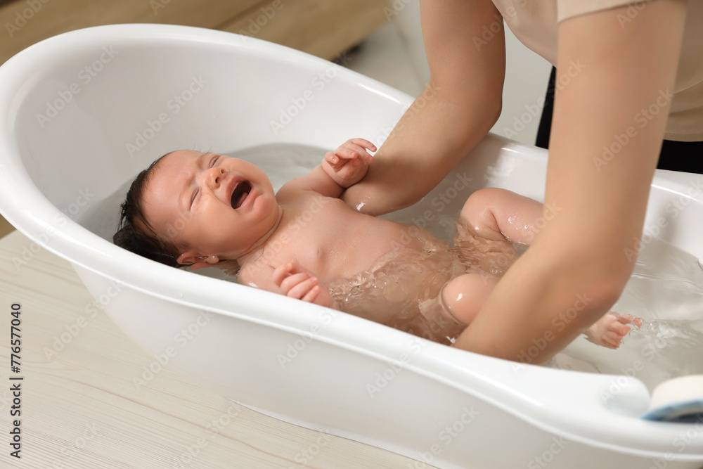 Mother bathing her little baby in bathtub, closeup Mother bathing her little baby in bathtub, closeup
