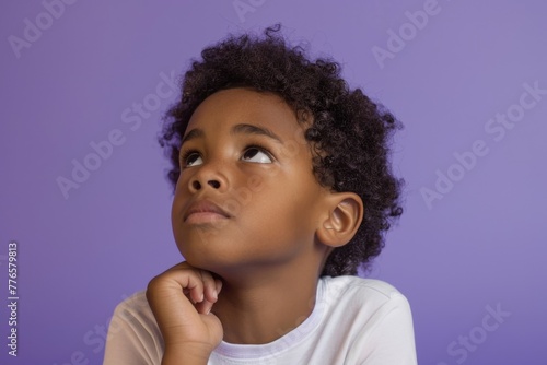 Pensive young African boy on violet background