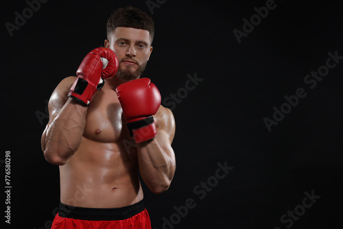 Man in boxing gloves on black background. Space for text