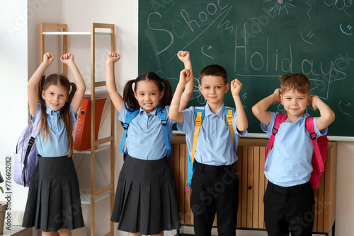 Cute little pupils near chalkboard in classroom. School holidays concept