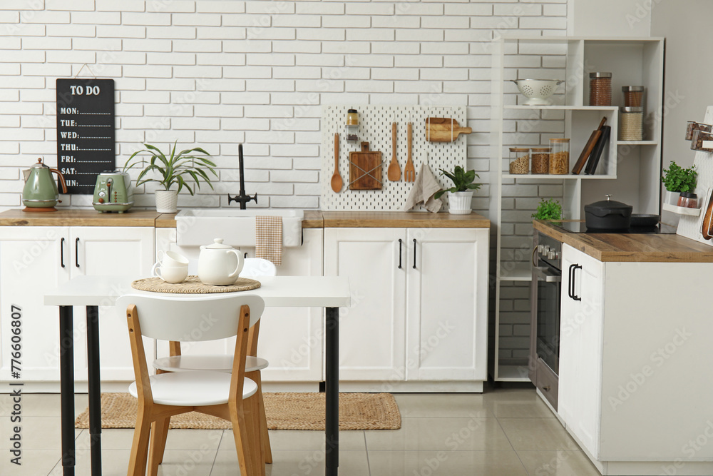 Fototapeta premium Stylish light kitchen with pegboard and modern dining table