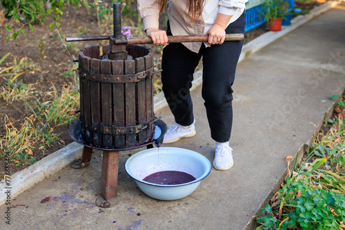 A woman works with a press to produce homemade farm wine. Background with selective focus