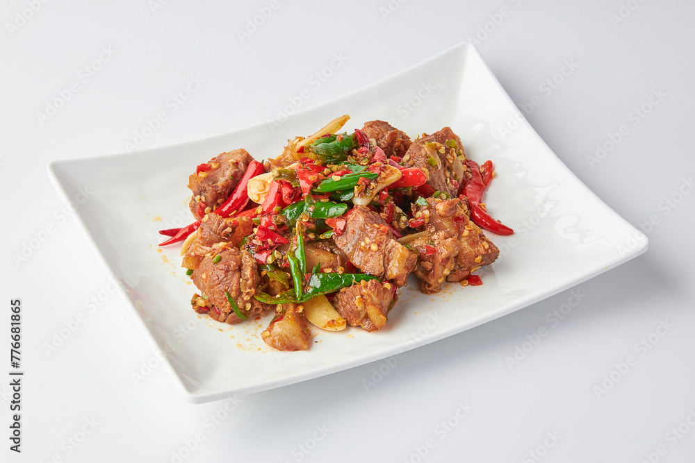 Stir-fried stewed beef shank with holy basil , chili and garlic served on white plate isolated on white background. Stir-fried holy basil is a very popular food in Thailand. Stir-fried stewed beef shank with holy basil , chili and garlic served on white plate isolated on white background. Stir-fried holy basil is a very popular food in Thailand.