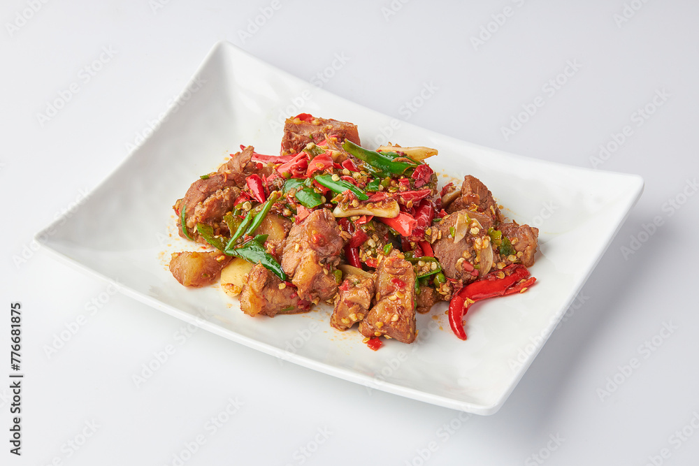 Stir-fried stewed beef shank with holy basil , chili and garlic served on white plate isolated on white background. Stir-fried holy basil is a very popular food in Thailand. Stir-fried stewed beef shank with holy basil , chili and garlic served on white plate isolated on white background. Stir-fried holy basil is a very popular food in Thailand.