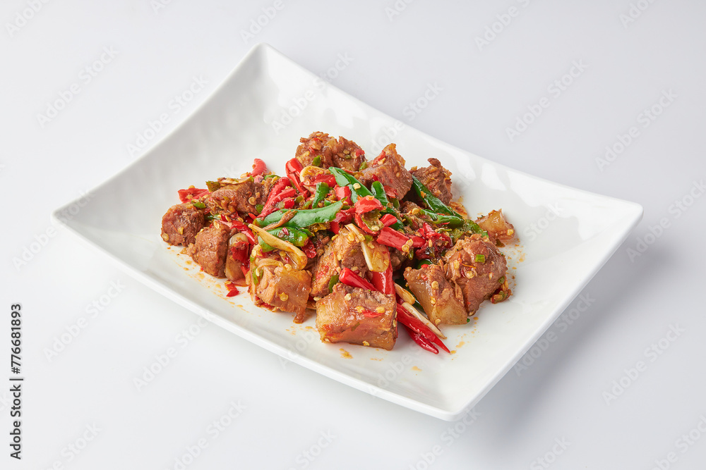 Stir-fried stewed beef shank with holy basil , chili and garlic served on white plate isolated on white background. Stir-fried holy basil is a very popular food in Thailand. Stir-fried stewed beef shank with holy basil , chili and garlic served on white plate isolated on white background. Stir-fried holy basil is a very popular food in Thailand.