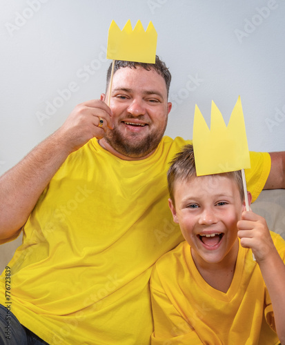 Portrait of dad and son in yellow clothes and with crowns