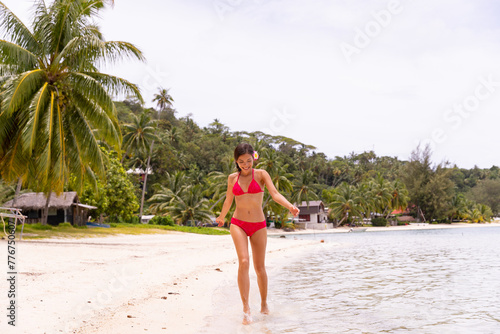 Beautiful bikini body woman playful on Bora Bora beach having fun playing splashing water. luxury travel vacation. This image is completely unretouched and model is with no makeup. Raw Image