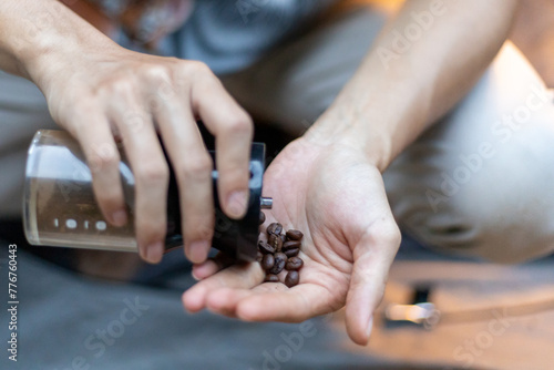 selective focus coffee beans Putting coffee beans into a hand grinder at a camping spot in the middle of nature in the morning.