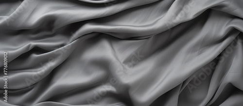 A detailed close-up of a gray fabric with numerous voluminous folds creating a textured surface photo