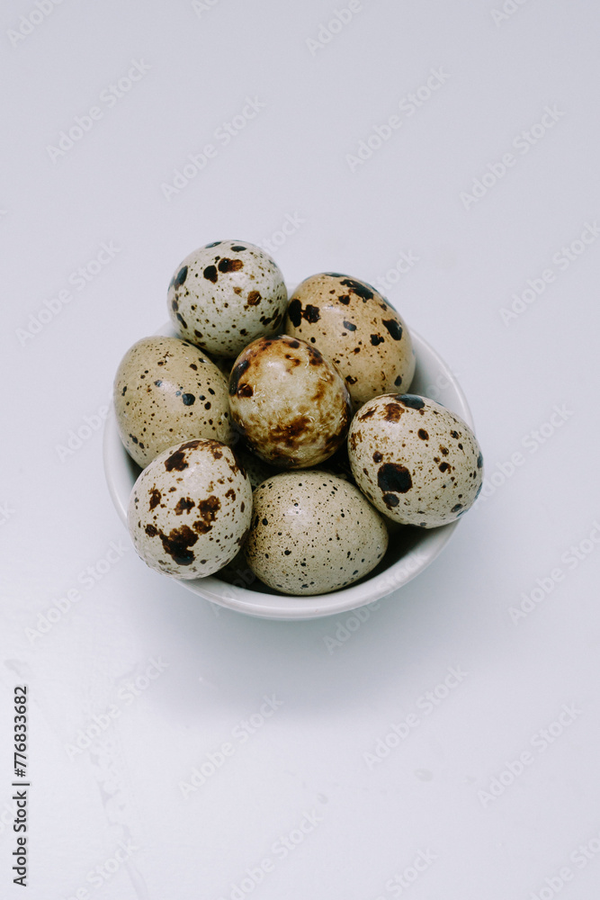Fototapeta premium Quail eggs that are the size of an adult human's thumb are lined up on a white mat for photographic and detailed purposes.