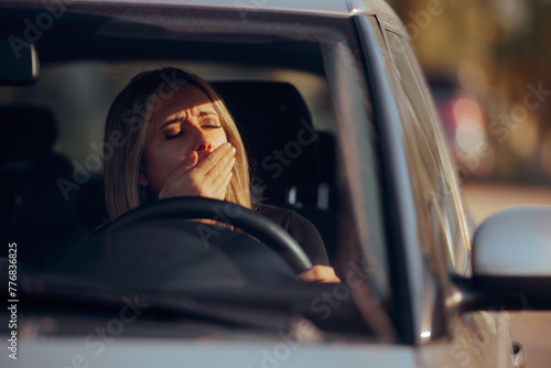 Driver Yawning Behind the Wheel in her Car. Sleepy drowsy woman trying to travel by car on a long distance drive 
