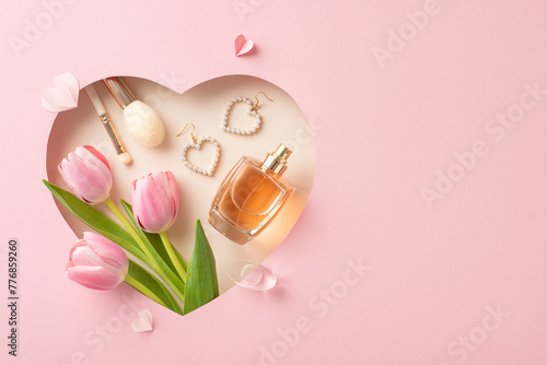 Mother's Day glamour top view shot: Fresh tulips, perfume, makeup essentials, jewelry, and paper hearts in a heart-shaped frame on pastel pink, with space for greetings or ads