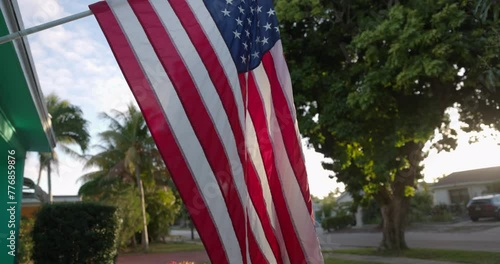 USA Flag hanging with pride in front of average american home at sunrise
