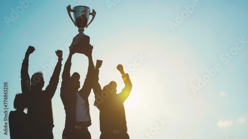 Team Lifting Trophy Against Sky. Capturing a victorious moment, this image features silhouettes of professionals raising a trophy together, embodying shared success and teamwork under a backlit sky.