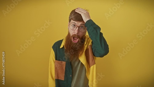 Redhead guy in glasses, hand on head in regret, realizes his idiotic memory lapse. mistake error vividly painted over isolated yellow backdrop. photo