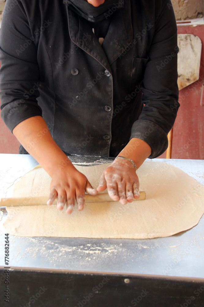 Hands of pizza maker man kneads dough, prepares and shapes for pizza base with rolling pin and flour Hands of pizza maker man kneads dough, prepares and shapes for pizza base with rolling pin and flour