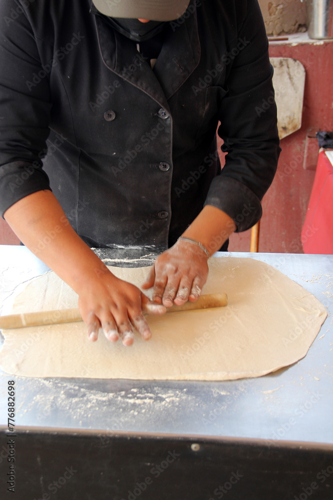 Hands of pizza maker man kneads dough, prepares and shapes for pizza base with rolling pin and flour