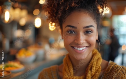 A woman with a yellow scarf is smiling at the camera. She is in a restaurant with a variety of food on the tables © imagineRbc