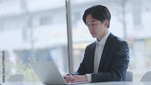 オフィスでパソコンを使って仕事をするスーツを着た若い日本人ビジネスマン	