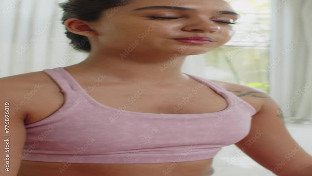 Vertical tilt up of female zoomer meditating in lotus position doing yoga at home Vertical tilt up of female zoomer meditating in lotus position doing yoga at home