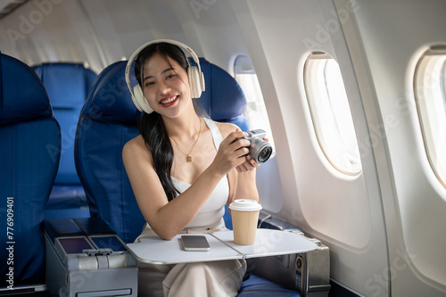 A beautiful Asian female passenger is taking pictures with her camera during the flight. © bongkarn