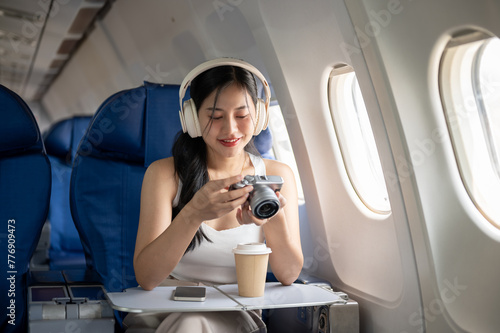 A female passenger is checking pictures on her camera during the flight of her summer vacation.