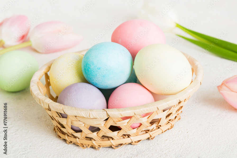 Happy Easter composition. Easter eggs in basket on colored table with yellow Tulips. Natural dyed colorful eggs background with copy space Happy Easter composition. Easter eggs in basket on colored table with yellow Tulips. Natural dyed colorful eggs background with copy space