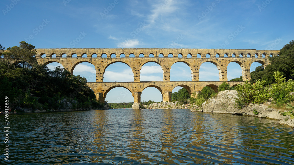 Pont du Gard famous aqueduct arched bridge mirroring in Gardon river, popular tourist landmark in France