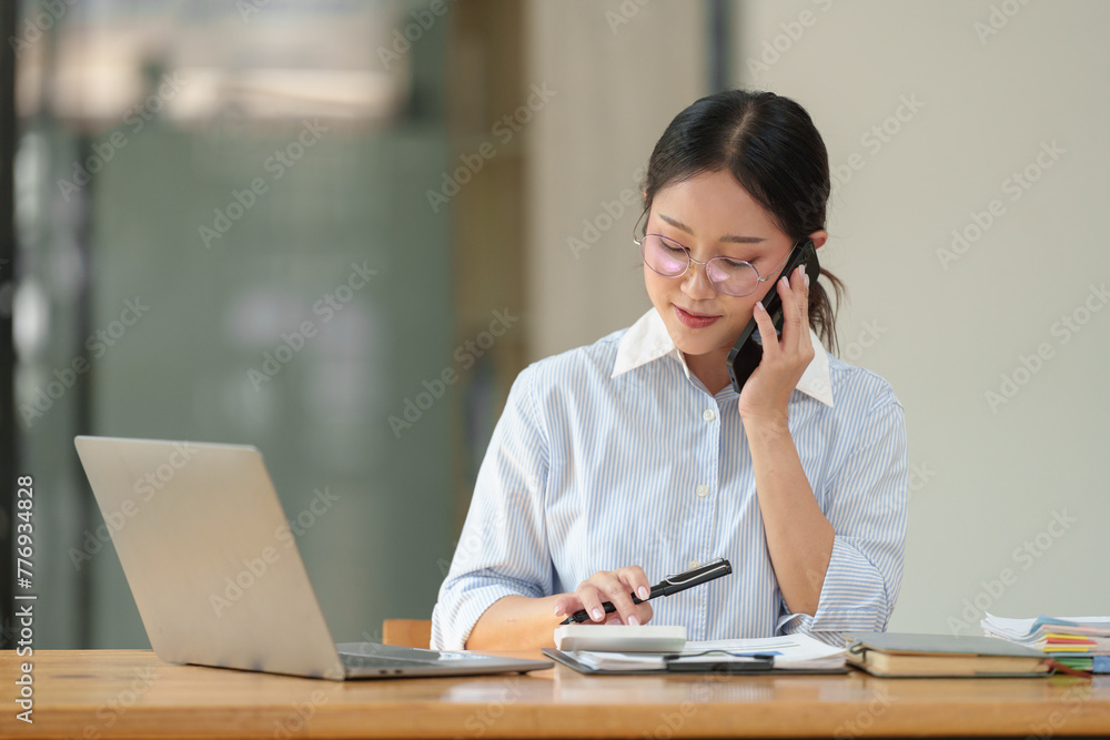 Asian businesswoman uses laptop and smartphone in open plan office business idea Data analysis, plans, marketing, calculations, accounting, auditing. Asian businesswoman uses laptop and smartphone in open plan office business idea Data analysis, plans, marketing, calculations, accounting, auditing.