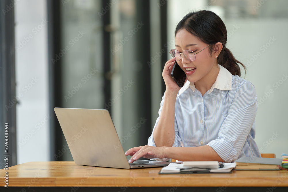 Asian businesswoman uses laptop and smartphone in open plan office business idea Data analysis, plans, marketing, calculations, accounting, auditing. Asian businesswoman uses laptop and smartphone in open plan office business idea Data analysis, plans, marketing, calculations, accounting, auditing.