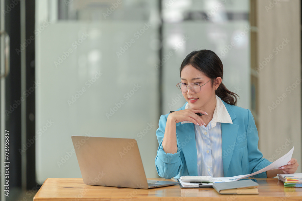Businesswoman wearing glasses sits and works with documents Work files to search and review in folders for analysis, calculations, financial planning and statistics, taxes and investment markets. Businesswoman wearing glasses sits and works with documents Work files to search and review in folders for analysis, calculations, financial planning and statistics, taxes and investment markets.