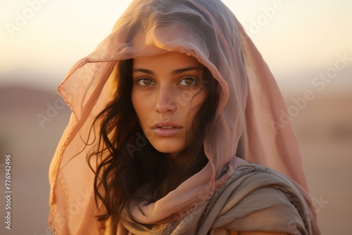 Candid shot of a young Bedouin woman, her veil gently fluttering in the desert breeze, showcasing the delicate intricacies of her pastel-hued garments © Hanna Haradzetska