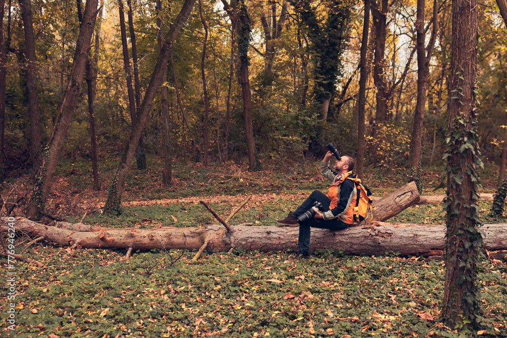 Man using binoculars and camera for bird and animal watching in Man using binoculars and camera for bird and animal watching in